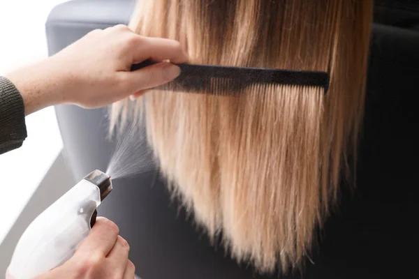 Cabeleireiro pentear cabelos longos de mulher jovem no salão — Fotografia de Stock
