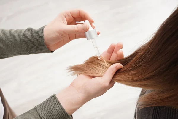 Alkalmazása a szérumot rá a fiatal nő a salon haj fodrász — Stock Fotó