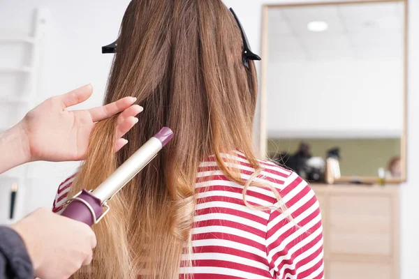 Hairdresser curling long hair of young woman in salon — Stock Photo, Image