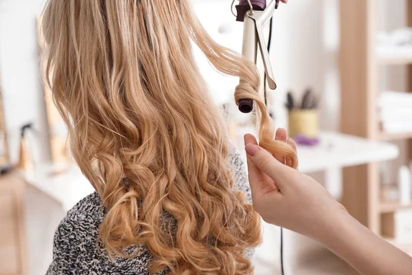 Парикмахер кёрлинг длинные волосы молодой женщины в салоне — стоковое фото
