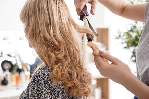 Перукарня кьорлінг довге волосся молодої жінки в салоні — стокове фото