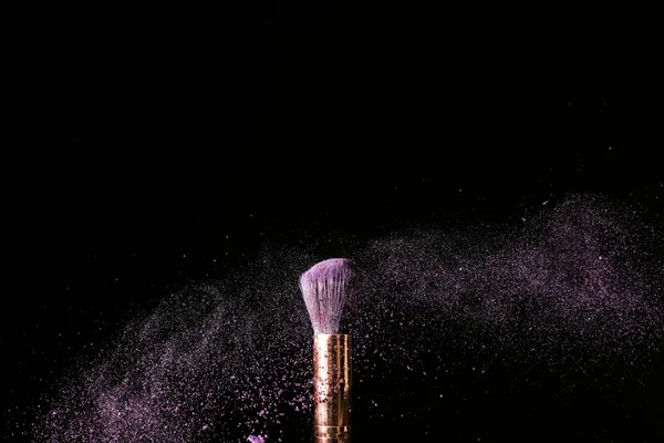 Make-up borstel en uitbarsting van eyeshadows op donkere achtergrond — Stockfoto