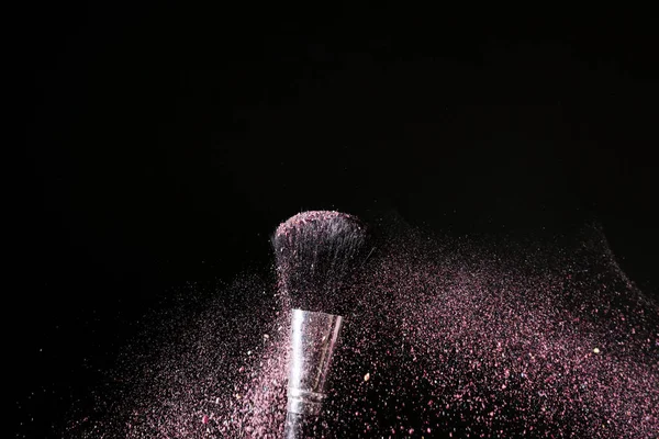Makeup brush and burst of eyeshadows on dark background — Stock Photo, Image