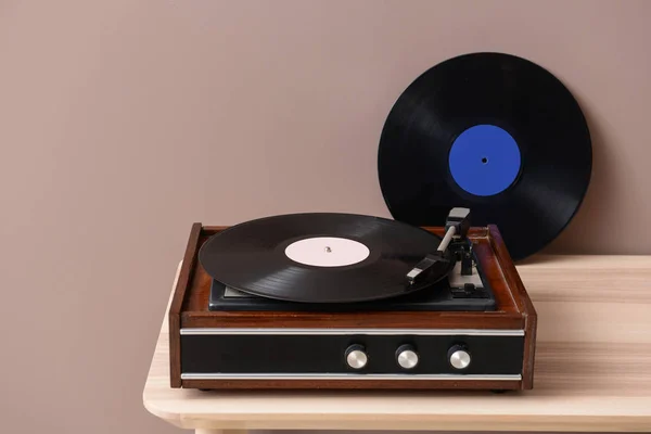 Gravador com disco de vinil na mesa perto da parede de cores — Fotografia de Stock