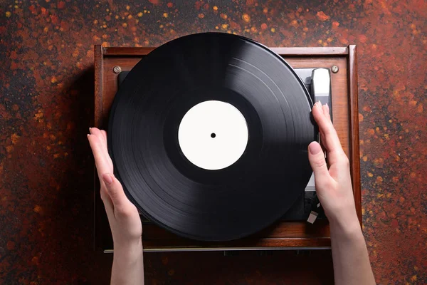 Vrouwelijke handen met vinyl schijf en platenspeler op grunge achtergrond — Stockfoto