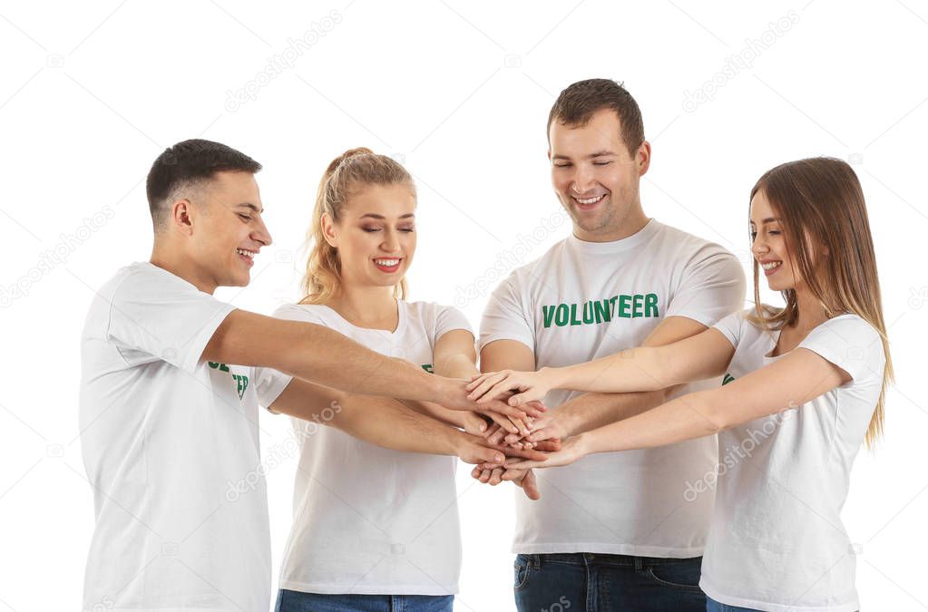 Team of young volunteers putting hands together on white background