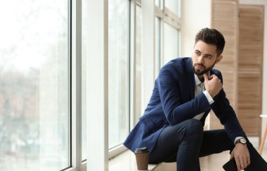 Pencere pervazına üzerinde oturan moda genç adam