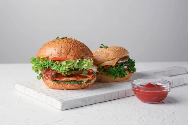 Board with tasty burgers on table — Stock Photo, Image