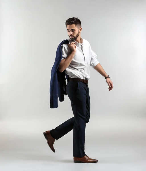 Модный молодой человек в формальной одежде ходит на светлом фоне — стоковое фото