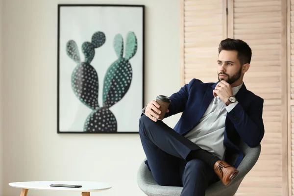 Fashionable young man sitting on chair indoors — Stock Photo, Image