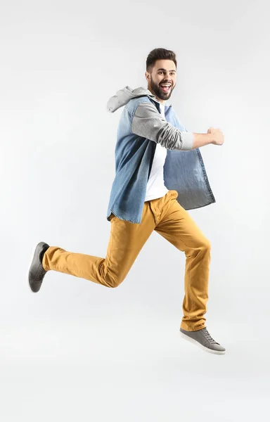 Fashionable jumping young man on light background