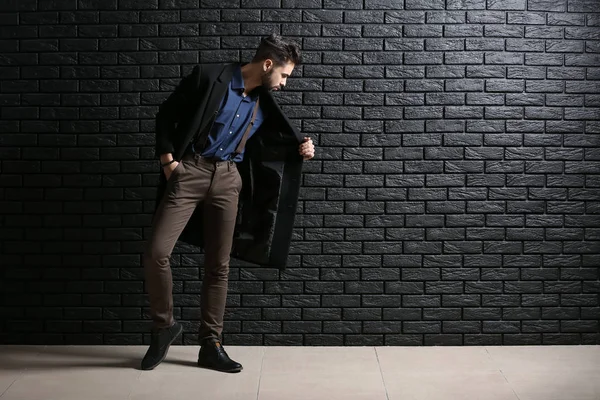 El joven a la moda contra la pared de ladrillo oscuro — Foto de Stock