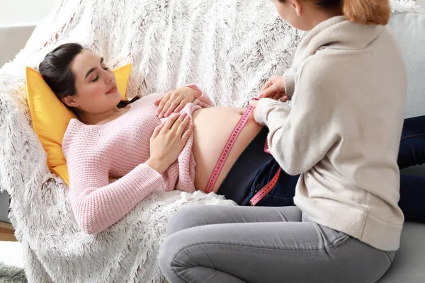Doula measuring belly of pregnant woman at home — Stock Photo, Image
