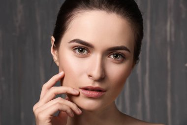 Gri arka planda güzel kaşları olan genç bir kadın.