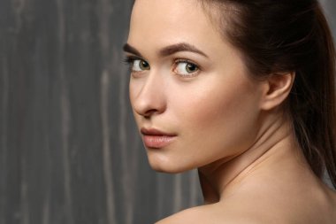 Gri arka planda güzel kaşları olan genç bir kadın.