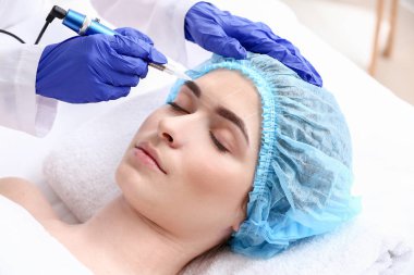 Güzellik salonunda kaş makyajı yapılan genç bir kadın.