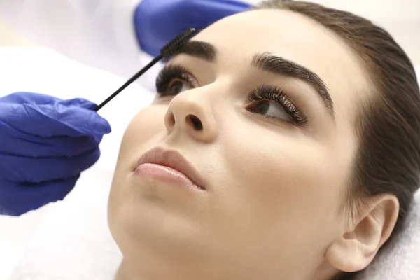 Young woman undergoing eyebrow correction procedure in beauty salon