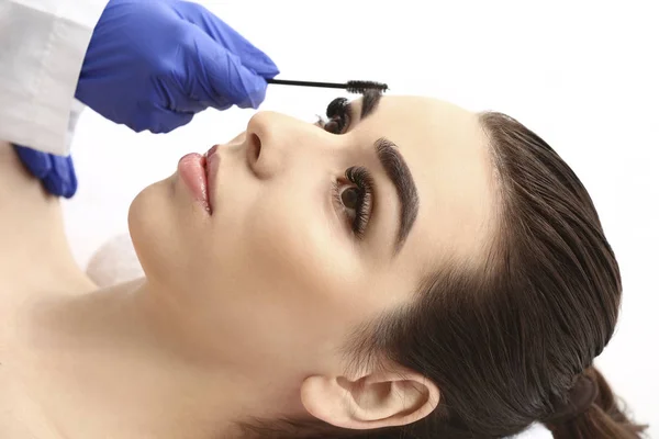 Young woman undergoing eyebrow correction procedure in beauty salon