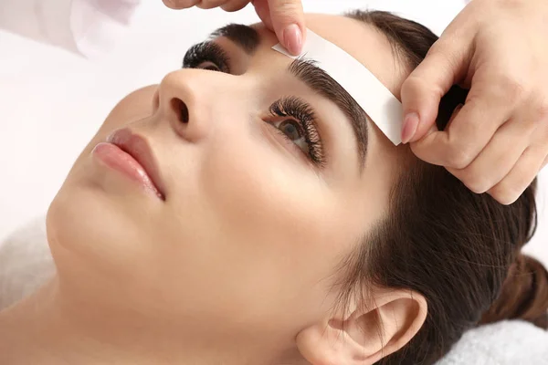 Young woman undergoing eyebrow correction procedure, waxing, wax