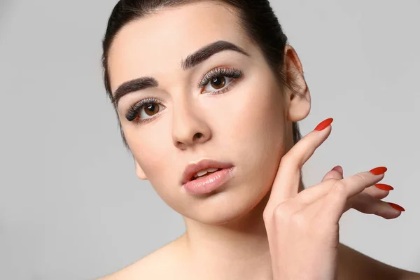 Mujer joven con hermosas cejas sobre fondo gris — Foto de Stock