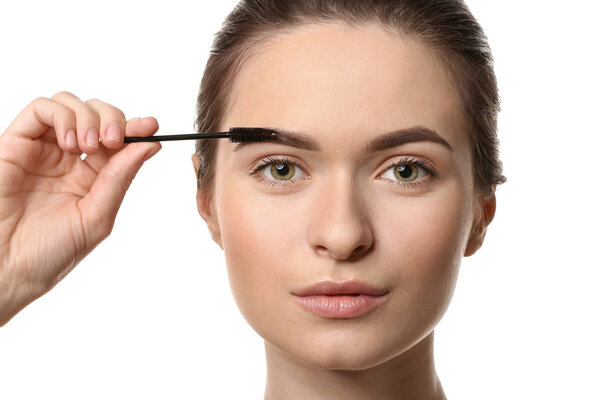 Young woman undergoing eyebrow correction procedure on white background