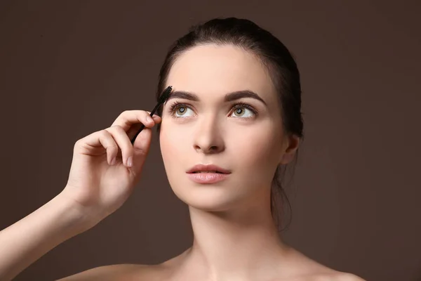 Mujer joven sometida a procedimiento de corrección de cejas sobre fondo de color — Foto de Stock