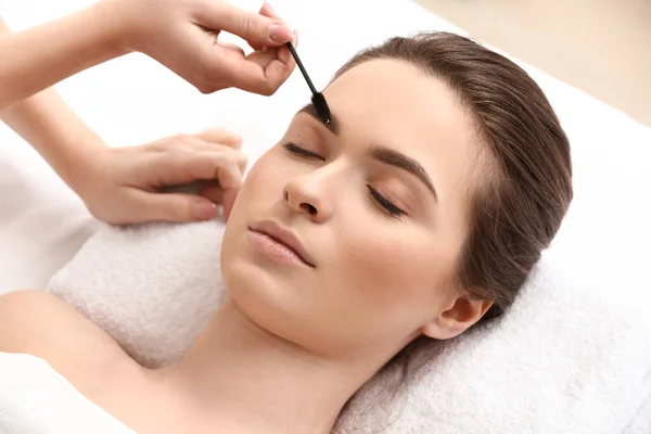 Young woman undergoing eyebrow correction procedure in beauty salon — Stock Photo, Image