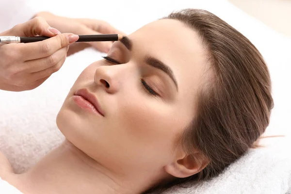 Young woman undergoing eyebrow correction procedure in beauty salon — Stock Photo, Image