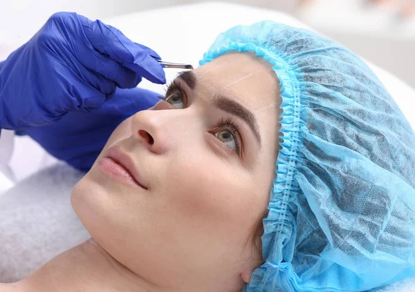 Young woman undergoing eyebrow correction procedure in beauty salon — Stock Photo, Image