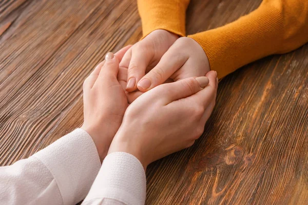 Hands of woman comforting her friend on wooden background — Stock Photo, Image