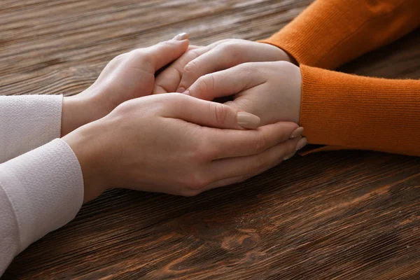 Hands of woman comforting her friend on wooden background — Stock Photo, Image