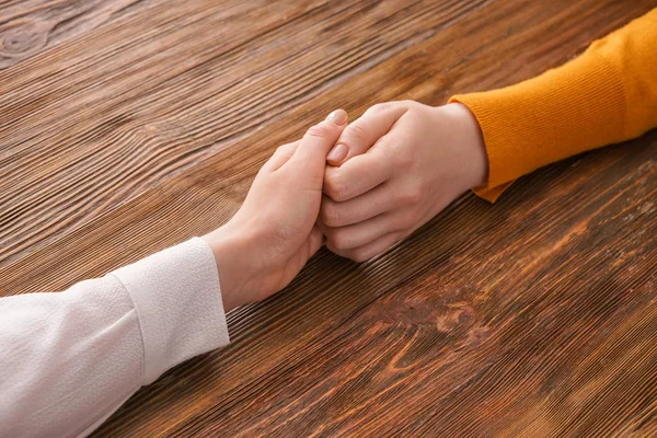 Young women holding hands on wooden background. Concept of support — Stock Photo, Image