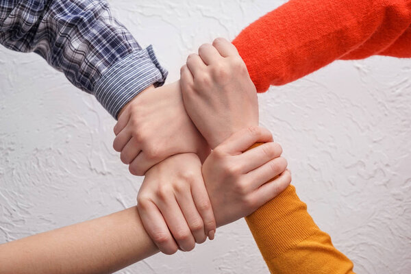 People putting hands together on light background