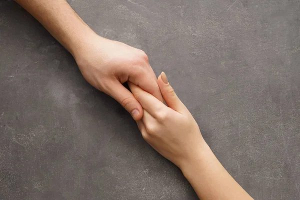 Hombre y mujer tomados de la mano sobre fondo gris —  Fotos de Stock