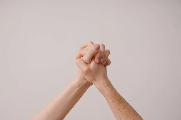 Mujeres jóvenes cogidas de la mano contra fondo claro — Foto de Stock