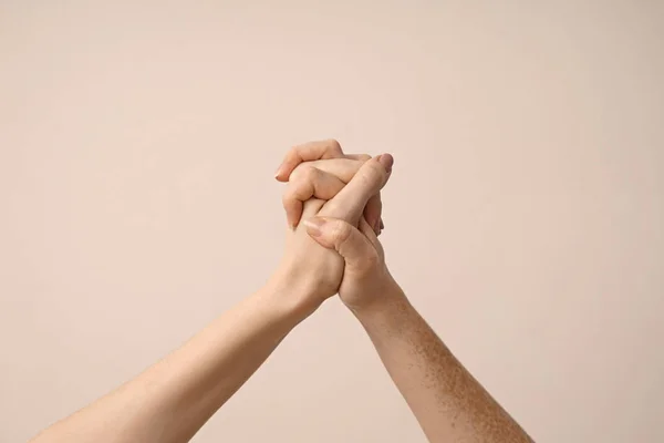 Mujeres jóvenes cogidas de la mano contra fondo claro — Foto de Stock