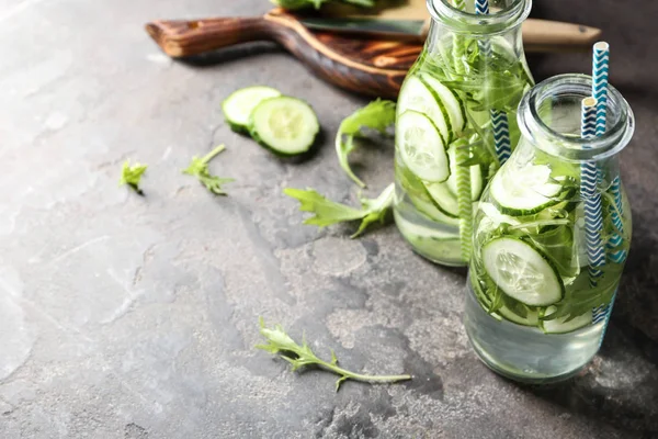 Bottles of cucumber water on grey table