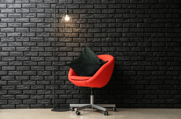 Modern armchair and lamp near dark brick wall — Stock Photo, Image