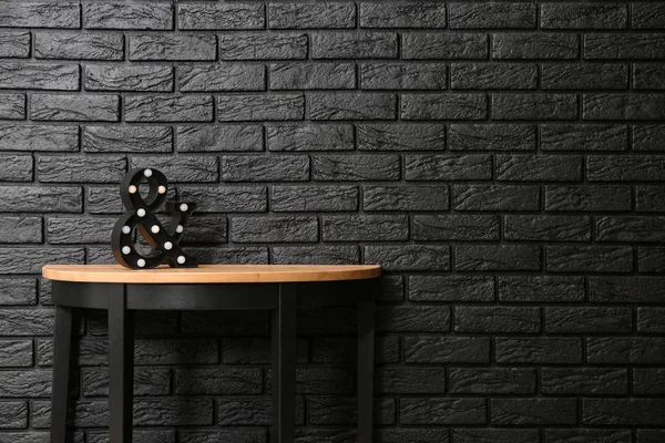 Modern table near dark brick wall — Stock Photo, Image