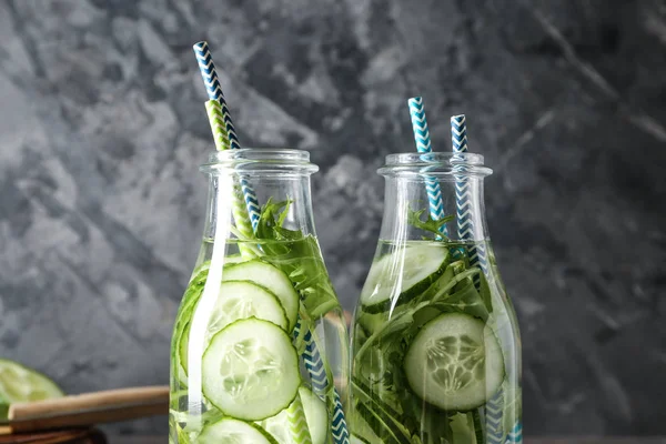 Bottles of cucumber water on grey background