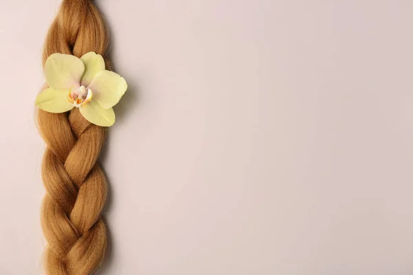 Плетемо нитку і квітку на світлому фоні. Концепція донорства волосся — стокове фото