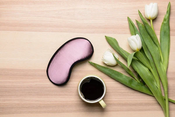 Samenstelling met slaap masker, bloemen en koffie op houten achtergrond — Stockfoto