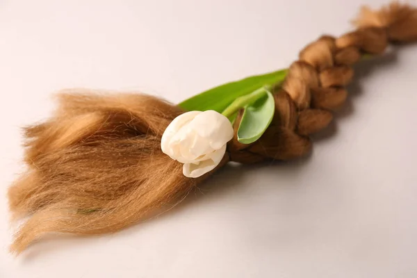 Braided strand and flower on light background. Concept of hair donation — Stock Photo, Image