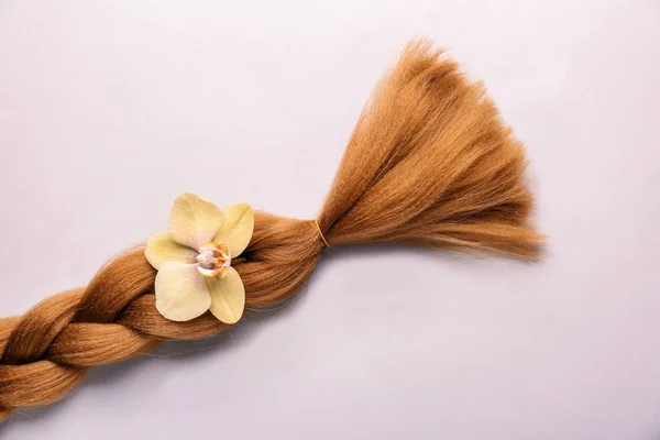 編み鎖と明るい背景の花。髪の寄付の概念 — ストック写真