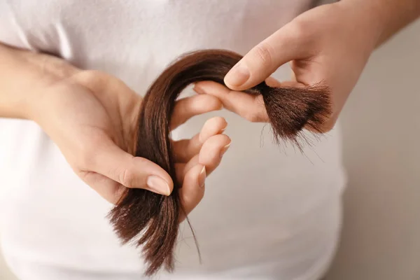 Mulher com fio de cabelo no fundo claro, close-up. Conceito de doação — Fotografia de Stock