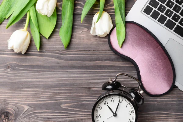 Composição com máscara de sono, laptop, flores e relógio em fundo de madeira — Fotografia de Stock