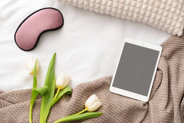 Spánku masku, květiny a tabletový počítač na posteli — Stock fotografie
