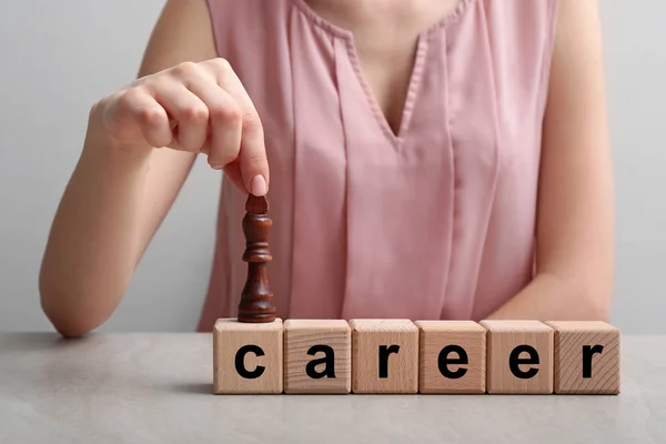 Woman with chess piece and word CAREER made of cubes on table. Concept of developing strategy for career growth — Stock Photo, Image
