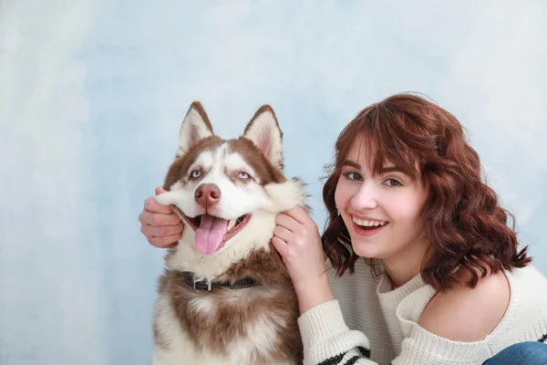 Young woman with her cute dog on color background — Stock Photo, Image