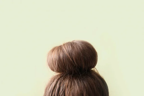 Young woman with hair bun on light background